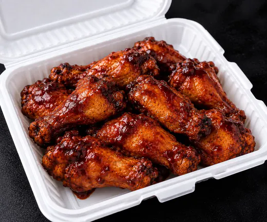 A clamshell of glazed BBQ wings